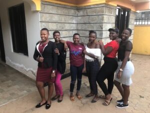 Six African women pose in front of a clinic