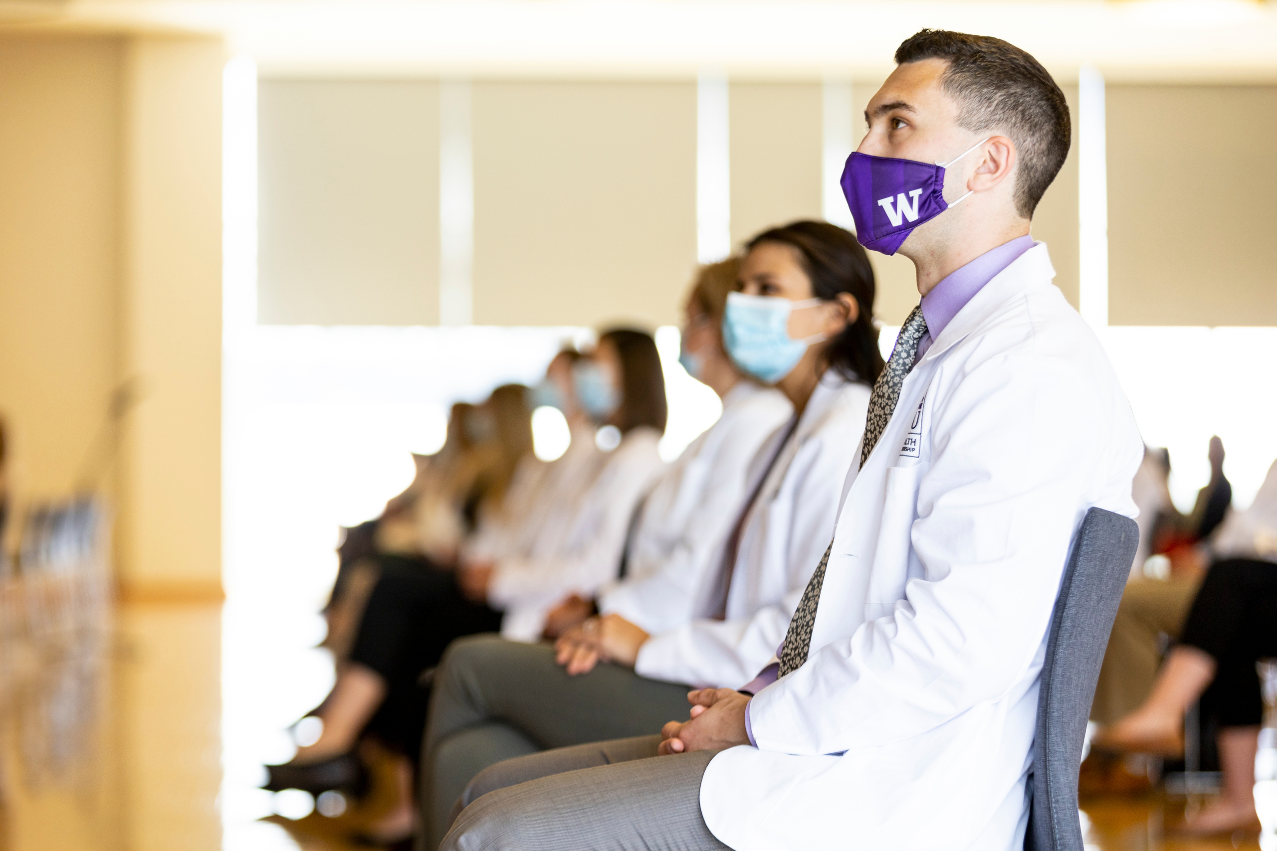 students masked and in white coats