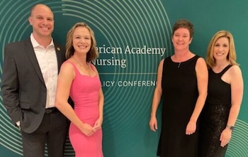 four faculty standing in front of green background