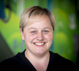 person smiling at camera with green background