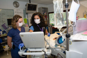 two persons standing in front of a hospital bed