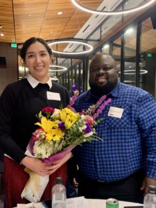 One person holding flowers and another person standing next to them.