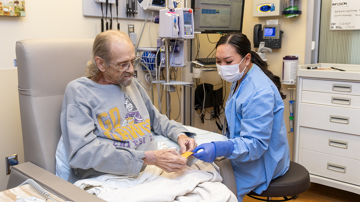 A registered nurse attending to an elderly patient in a hospital room.