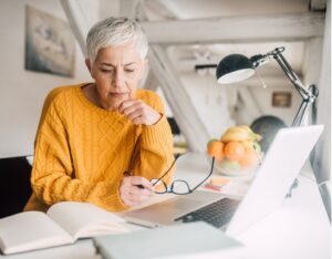 women wearing yellow sweater with book and laptop open