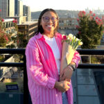 Woman posing for camera and smiling and holding flowers in her hands