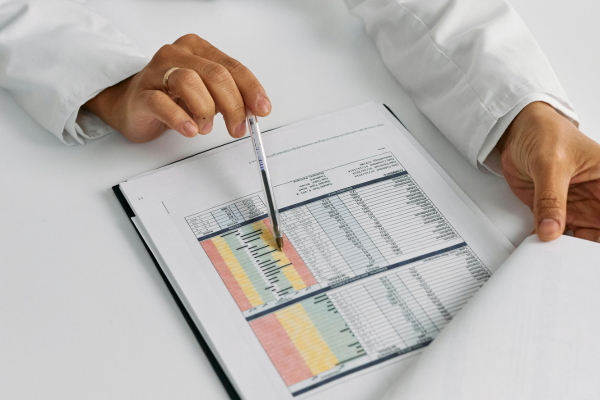 Person pointing to a printed spreadsheet with a pen