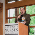A man standing at a podium and speaking at the King County Nurses Association scholarship gala.