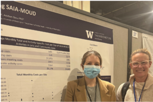 Two researchers pose beside a University of Washington research poster during an academic conference poster session.