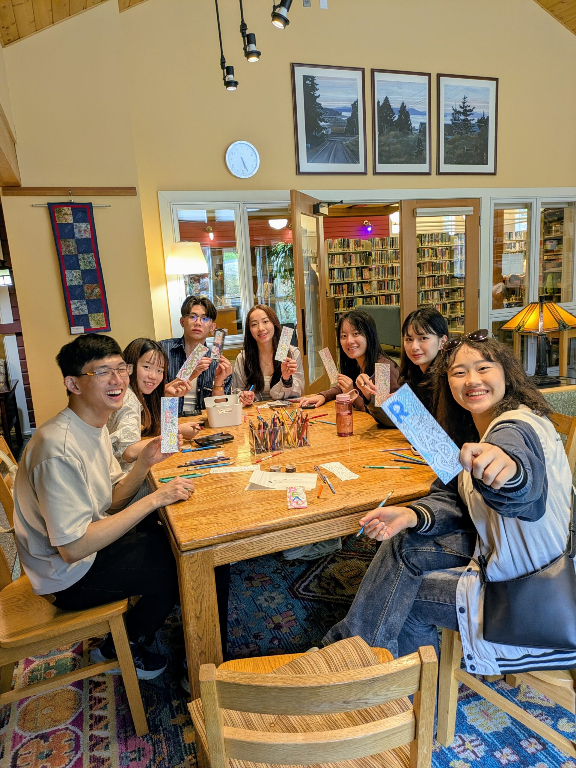 Group of people around table holding up drawings colored with colored pencil